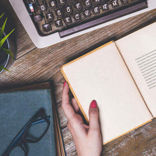 Typewriter and woman's hand holding book